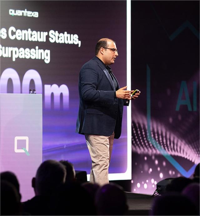 Vishal Marria on stage giving a presentation about Centaur Status, holding a phone, with a large screen displaying text in the background.
